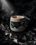 White Satin Riot textured white-stone candle lit among shattered glass and white satin — Ironic Paradoxists