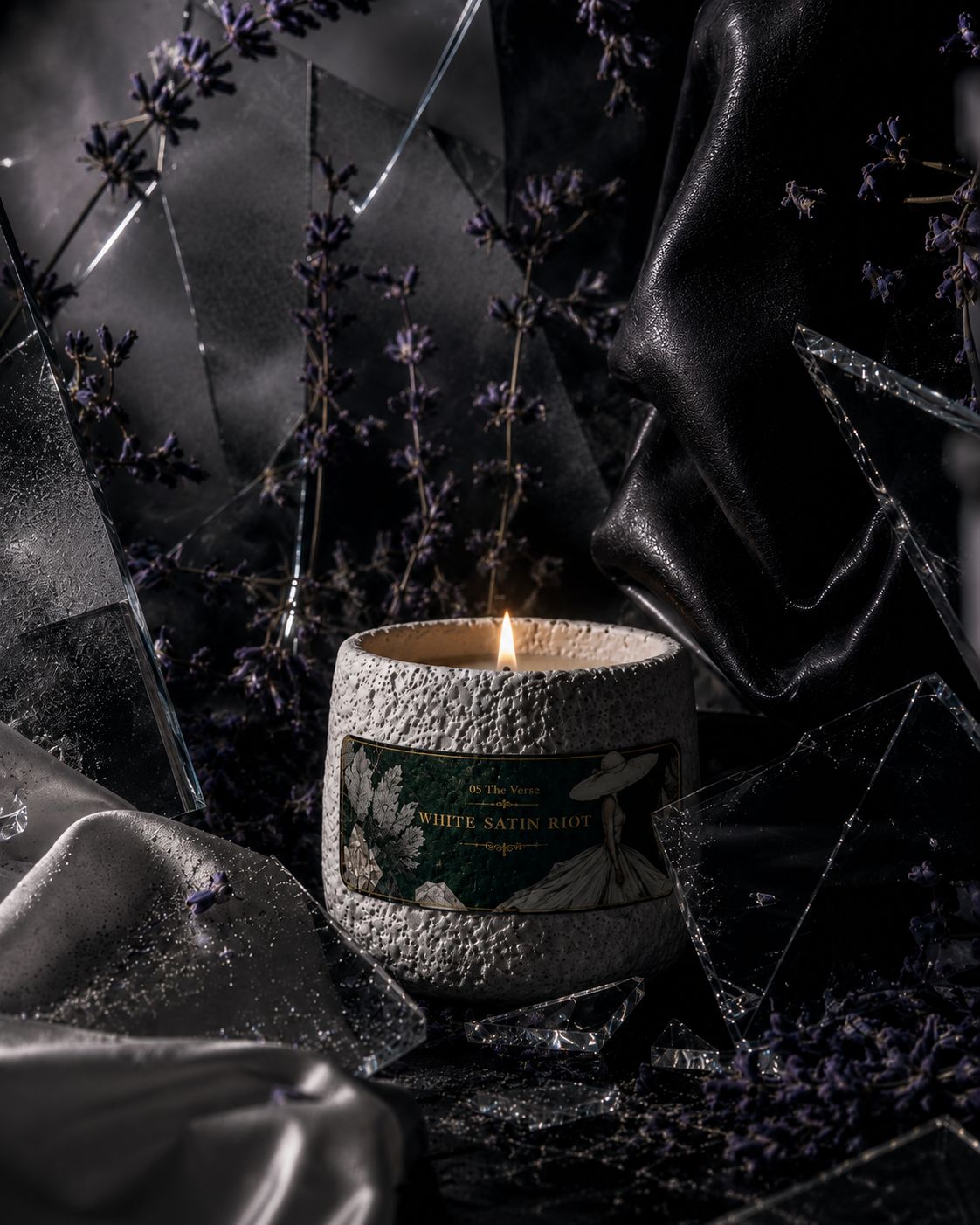 White Satin Riot candle among shattered glass, satin and lavender in dark light
